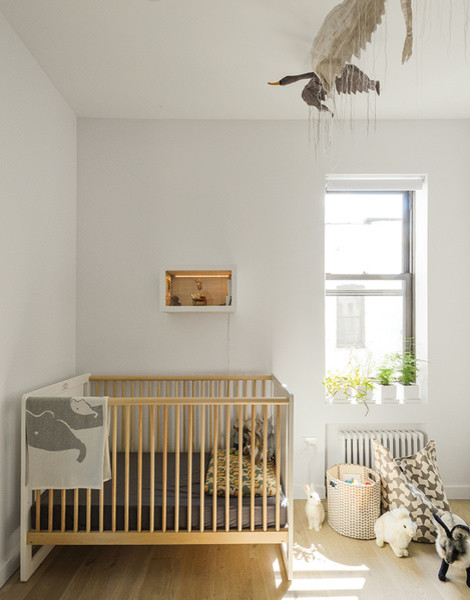 Cette photo montre une petite chambre de bébé neutre avec un mur blanc et un sol en bois brun.