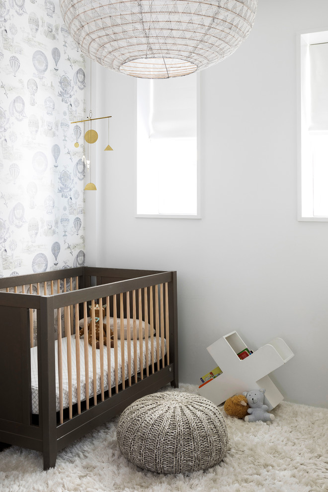 Cette photo montre une chambre de bébé neutre moderne de taille moyenne avec un mur blanc et un sol en bois brun.