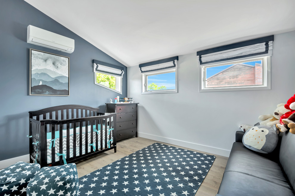 Imagen de habitación de bebé neutra contemporánea de tamaño medio con paredes azules y suelo de madera clara