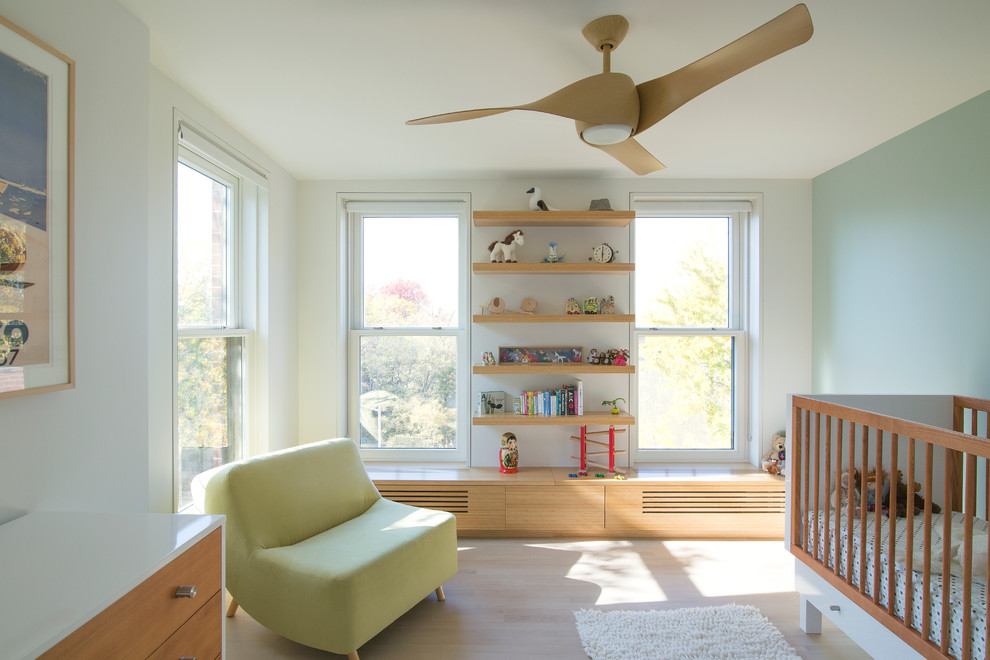 Modelo de habitación de bebé neutra actual de tamaño medio con paredes multicolor y suelo de madera clara