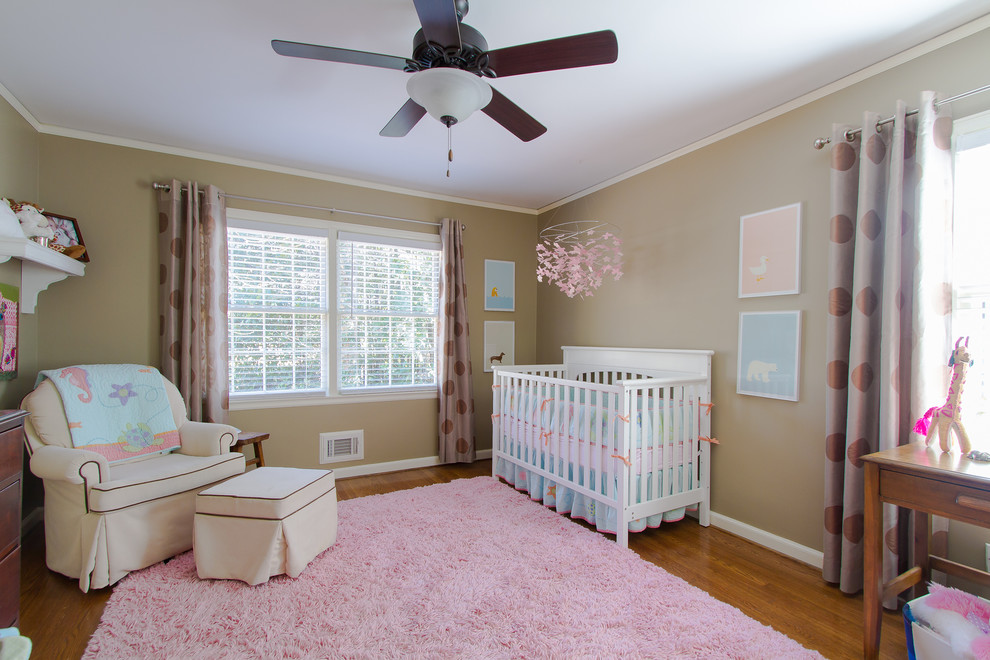 This is an example of a medium sized classic nursery for girls in Atlanta with beige walls and medium hardwood flooring.