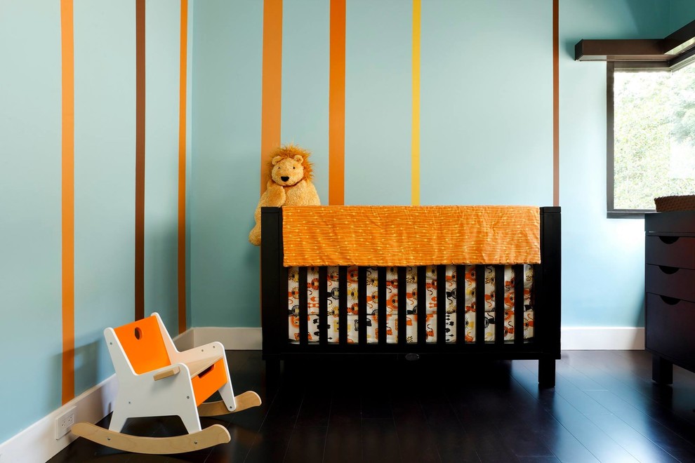 Aménagement d'une chambre de bébé neutre contemporaine de taille moyenne avec un mur bleu et parquet foncé.