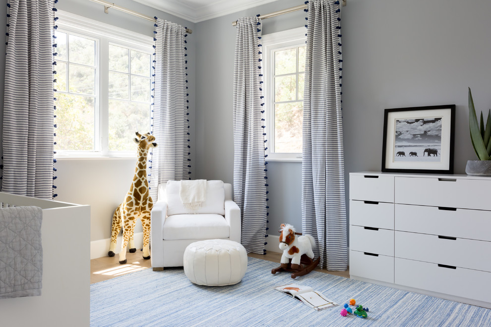 Modelo de habitación de bebé neutra costera de tamaño medio con paredes grises y suelo de madera clara
