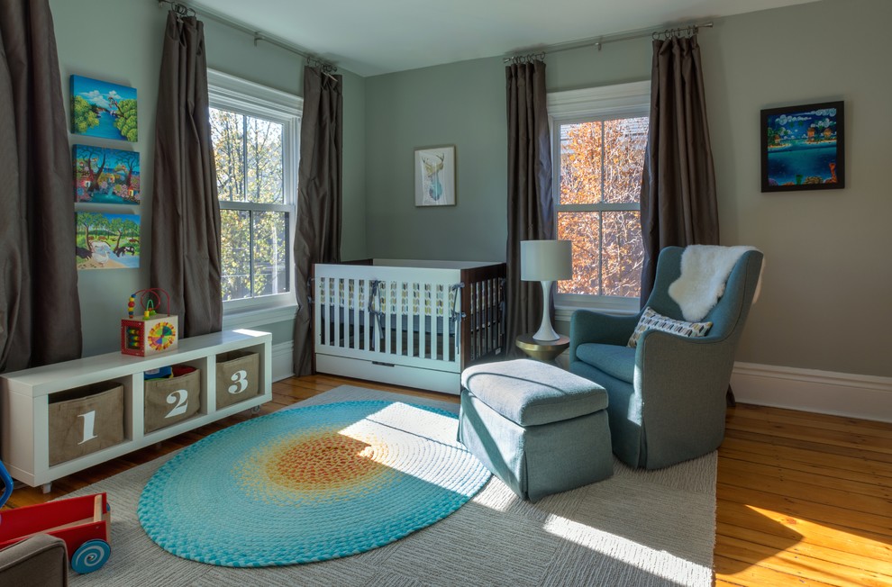 Ejemplo de habitación de bebé neutra moderna con paredes azules y suelo de madera en tonos medios