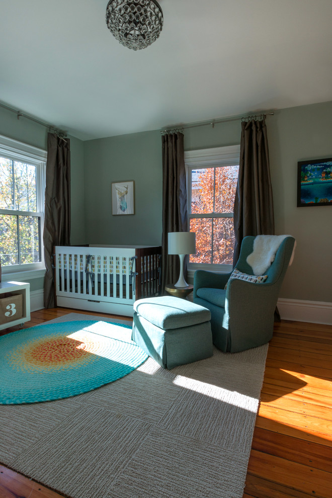 Aménagement d'une chambre de bébé neutre moderne avec un mur bleu et un sol en bois brun.