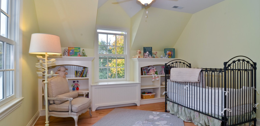 Cette photo montre une chambre de bébé neutre chic de taille moyenne avec un mur jaune et un sol en bois brun.