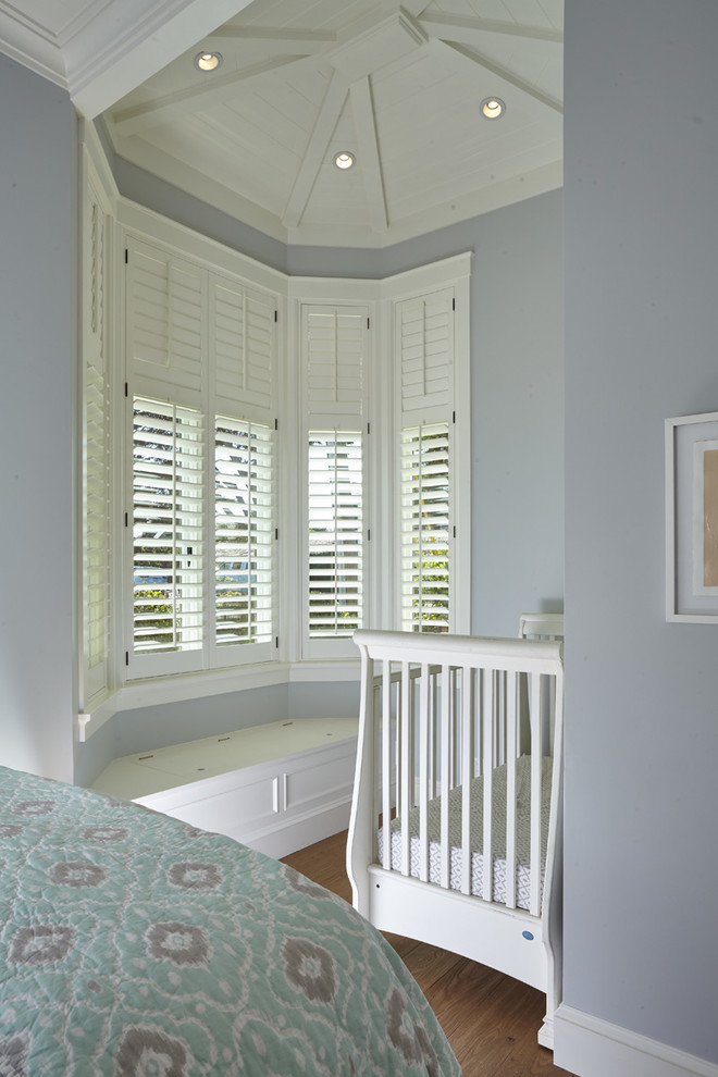 Foto de habitación de bebé neutra costera de tamaño medio con paredes azules y suelo de madera en tonos medios