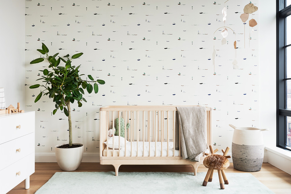 Scandi gender neutral nursery in New York with multi-coloured walls and light hardwood flooring.