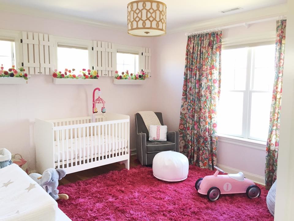 Immagine di una cameretta per neonata tradizionale di medie dimensioni con pareti rosa e pavimento in legno massello medio