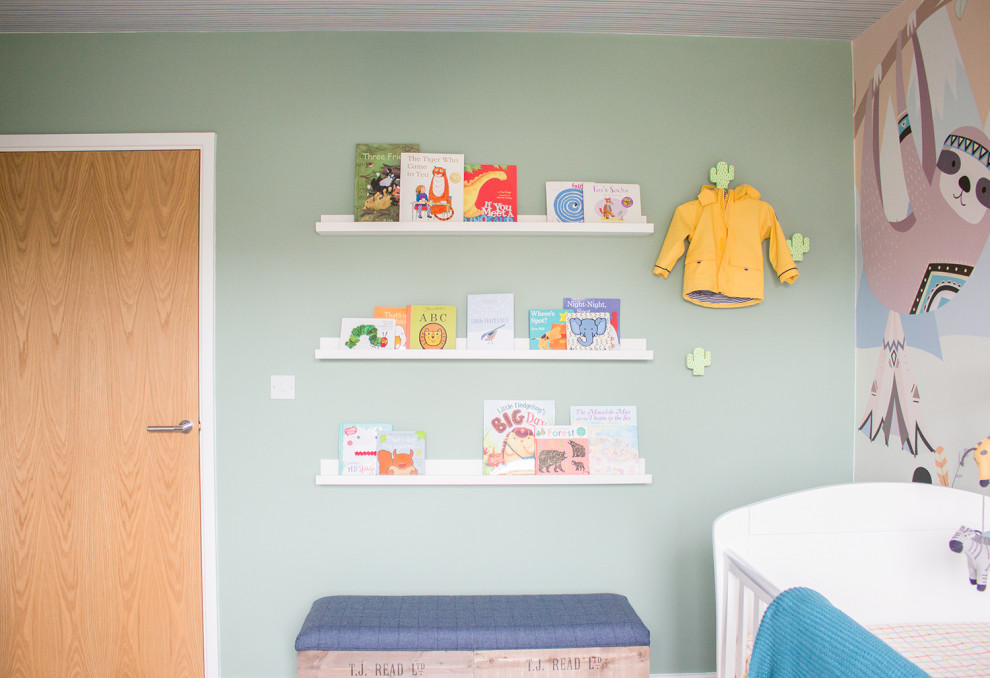 Modelo de habitación de bebé neutra contemporánea de tamaño medio con paredes verdes, moqueta y suelo beige