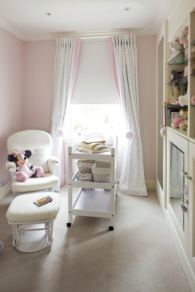 Inspiration for a classic nursery for girls in London with pink walls and carpet.