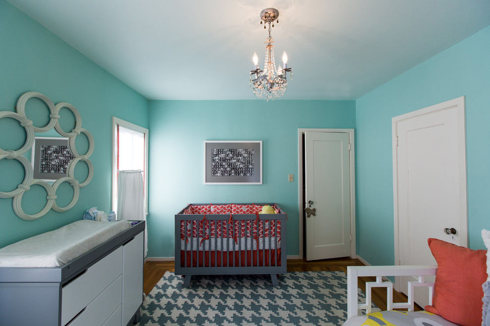 Foto på ett mellanstort funkis könsneutralt babyrum, med blå väggar och mellanmörkt trägolv