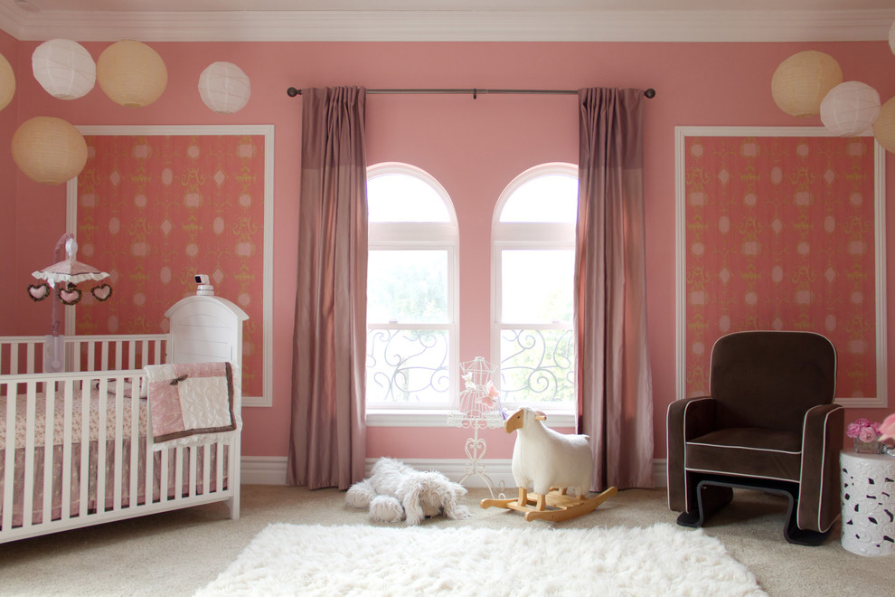Classic nursery for girls in Los Angeles with pink walls and carpet.