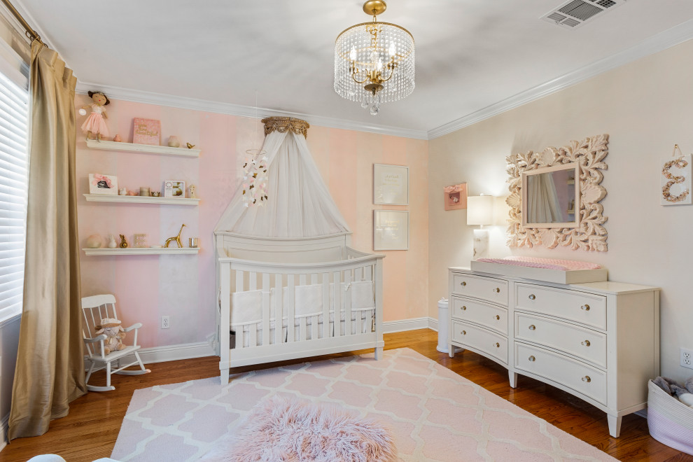 Klassisches Babyzimmer mit rosa Wandfarbe, braunem Holzboden und braunem Boden in New Orleans