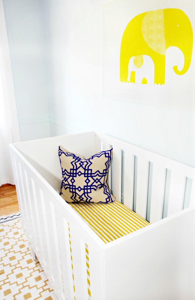 Example of a mid-sized trendy gender-neutral medium tone wood floor nursery design in Baltimore with blue walls