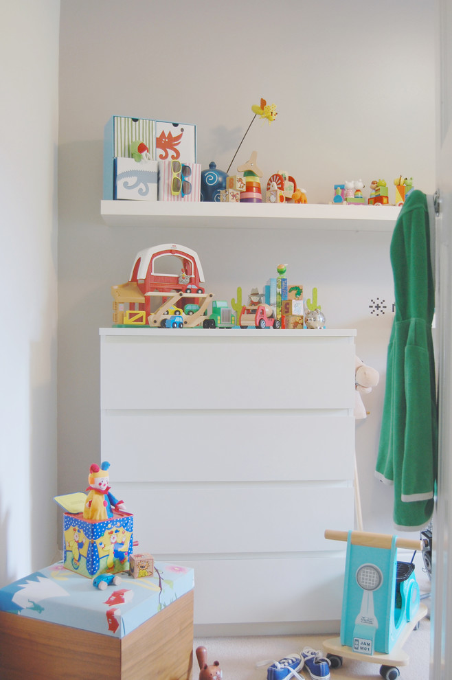 Imagen de habitación de bebé neutra moderna pequeña con paredes multicolor, moqueta y suelo beige