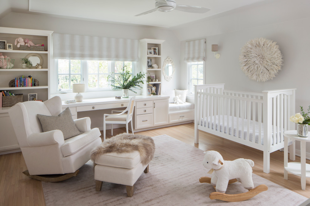Esempio di una cameretta per neonati neutra chic di medie dimensioni con pareti bianche, parquet chiaro e pavimento beige