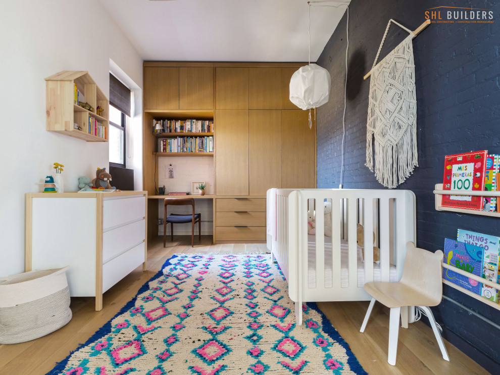 Medium sized modern gender neutral nursery in New York with grey walls, laminate floors, beige floors and brick walls.