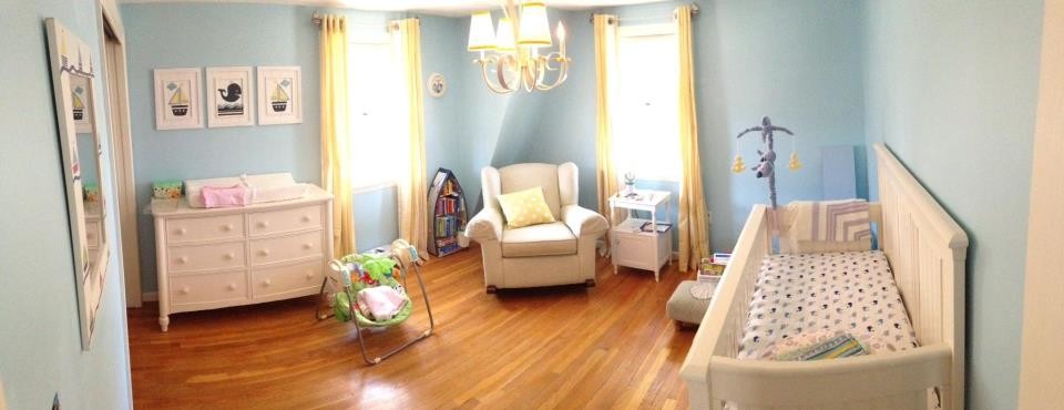 Modelo de habitación de bebé neutra marinera de tamaño medio con paredes azules y suelo de madera clara