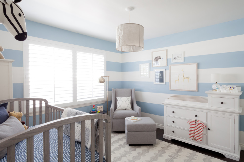 Exemple d'une chambre de bébé garçon chic de taille moyenne avec un mur bleu et parquet foncé.