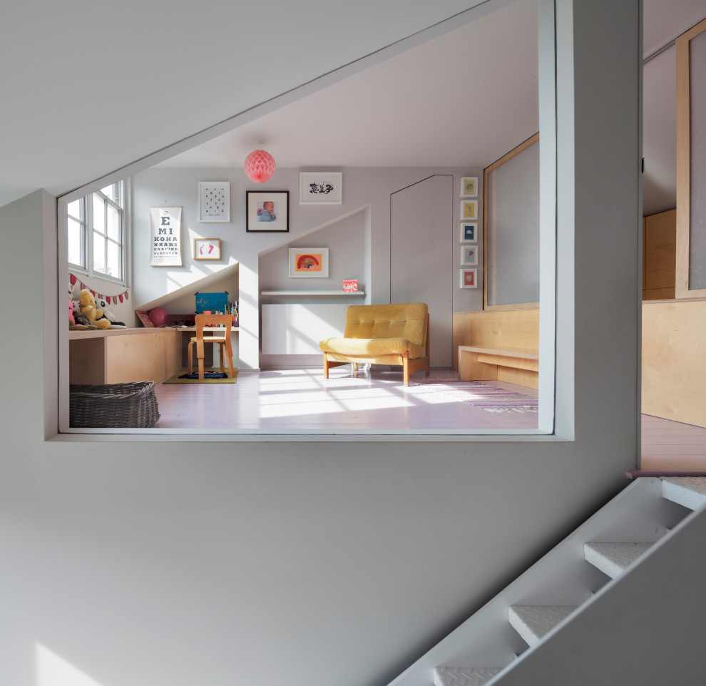 Imagen de habitación de bebé neutra contemporánea pequeña con paredes grises, suelo de madera pintada, suelo rosa y panelado
