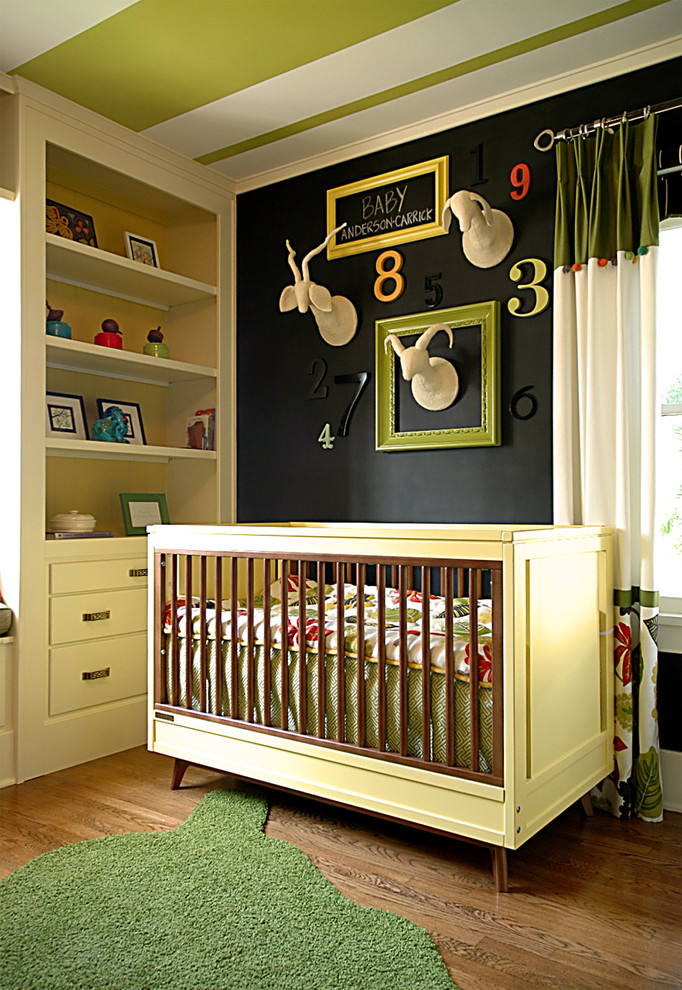 Cette photo montre une chambre de bébé neutre tendance avec un mur noir et parquet foncé.