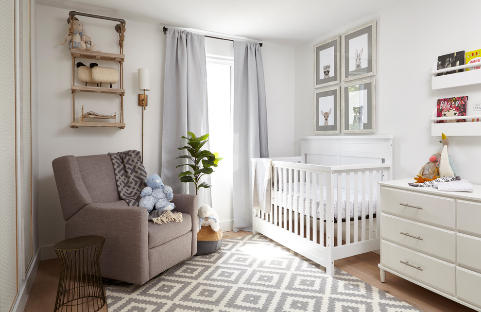 Cette image montre une chambre de bébé neutre design avec un mur blanc, un sol en bois brun et un sol marron.