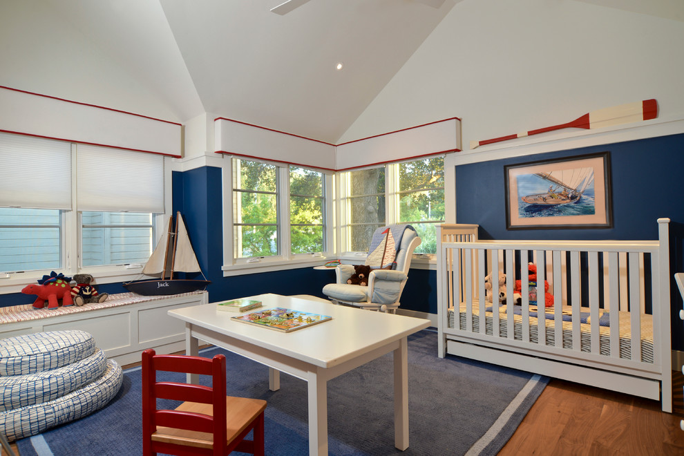 Imagen de habitación de bebé niño tradicional grande con paredes azules y suelo de madera en tonos medios
