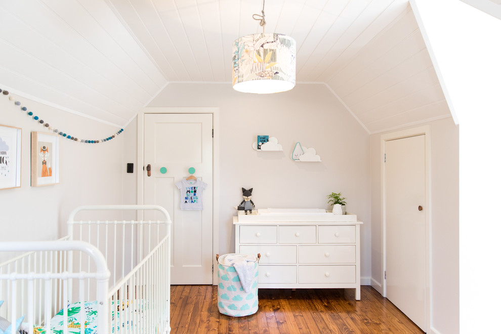 Diseño de habitación de bebé neutra tradicional renovada grande con paredes beige y suelo de madera en tonos medios