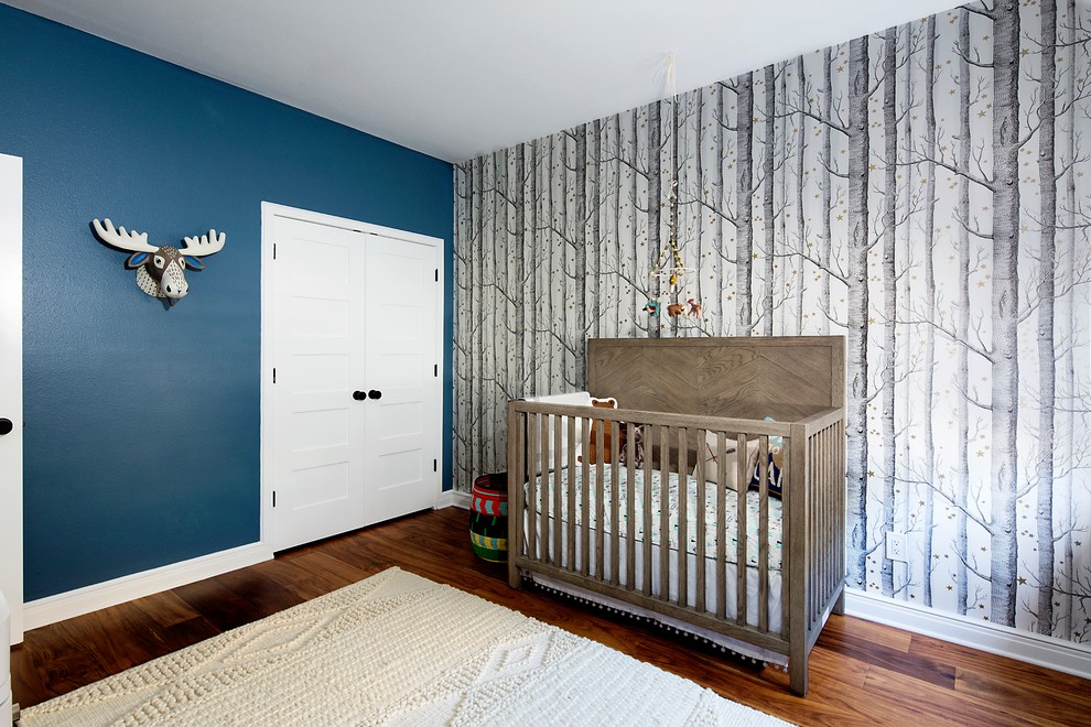 Diseño de habitación de bebé neutra contemporánea de tamaño medio con paredes azules, suelo de madera oscura y suelo marrón
