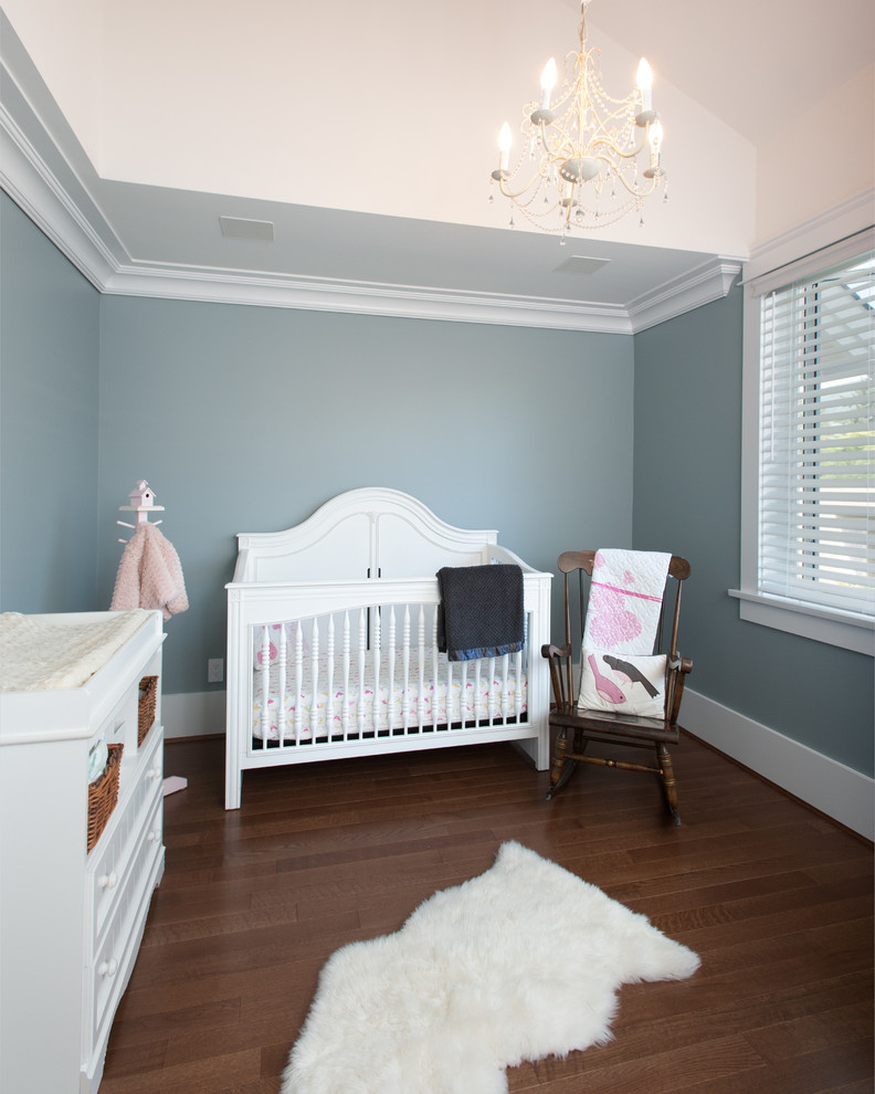 Diseño de habitación de bebé neutra de estilo americano de tamaño medio con paredes grises y suelo de madera en tonos medios