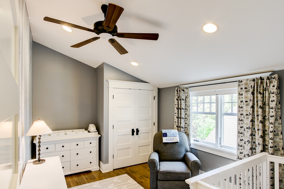 Foto de habitación de bebé neutra de estilo americano de tamaño medio con paredes grises y suelo de madera en tonos medios