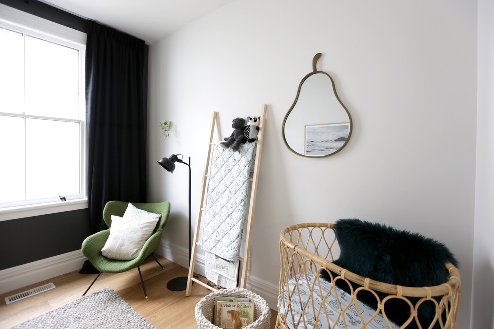 Immagine di una piccola cameretta per neonato contemporanea con pareti bianche e parquet chiaro
