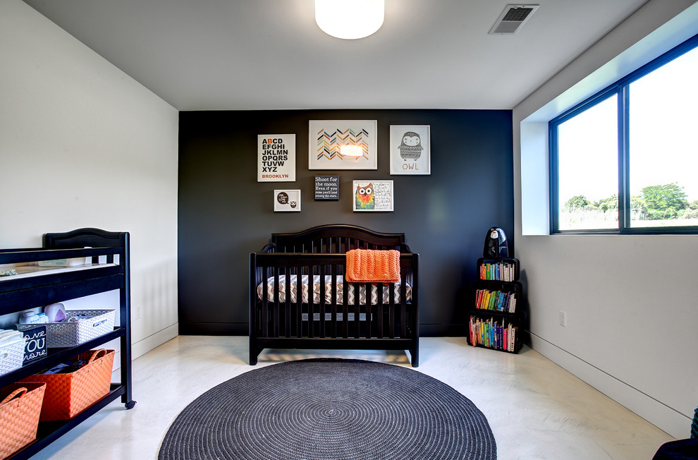 Modelo de habitación de bebé neutra contemporánea de tamaño medio con paredes negras y suelo de cemento
