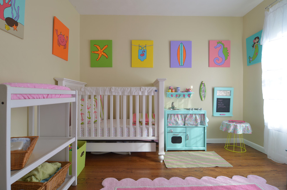 Design ideas for a medium sized beach style nursery for girls in Dallas with beige walls and medium hardwood flooring.