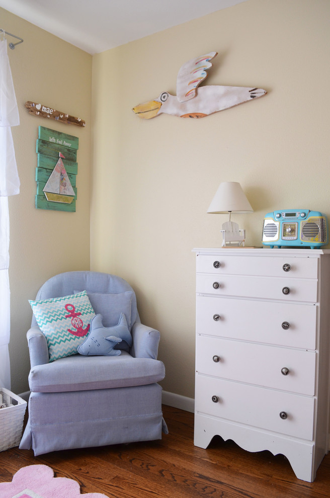 Inspiration pour une chambre de bébé neutre marine avec un mur beige, un sol en bois brun et un sol orange.