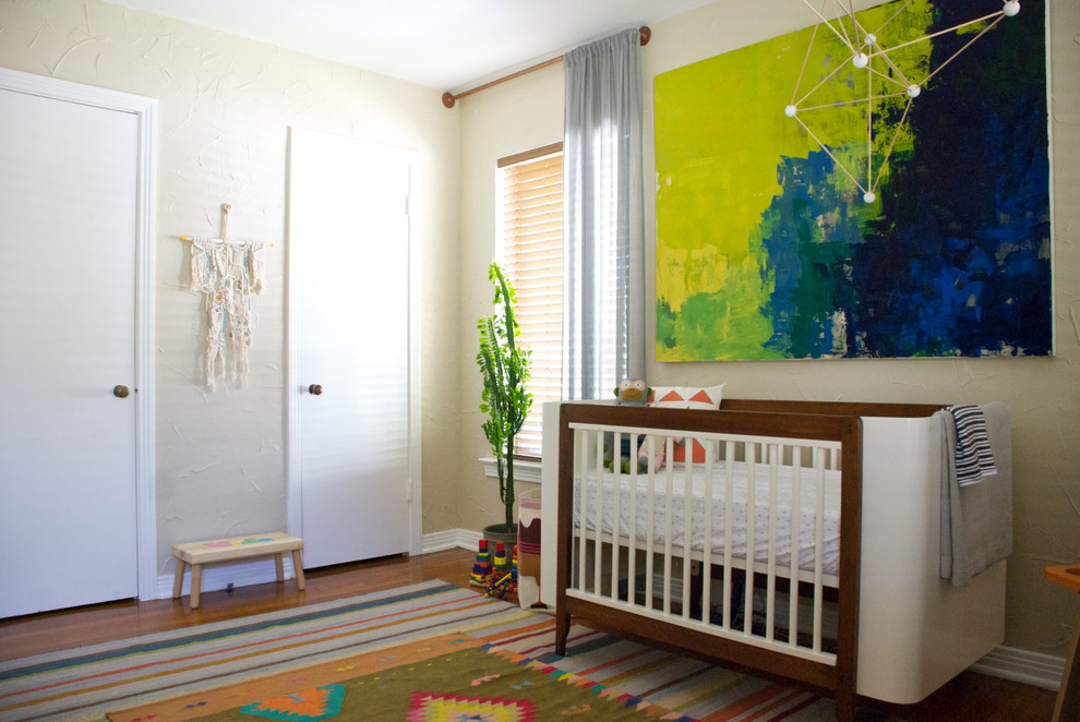 This is an example of an eclectic gender neutral nursery in Dallas with beige walls and medium hardwood flooring.