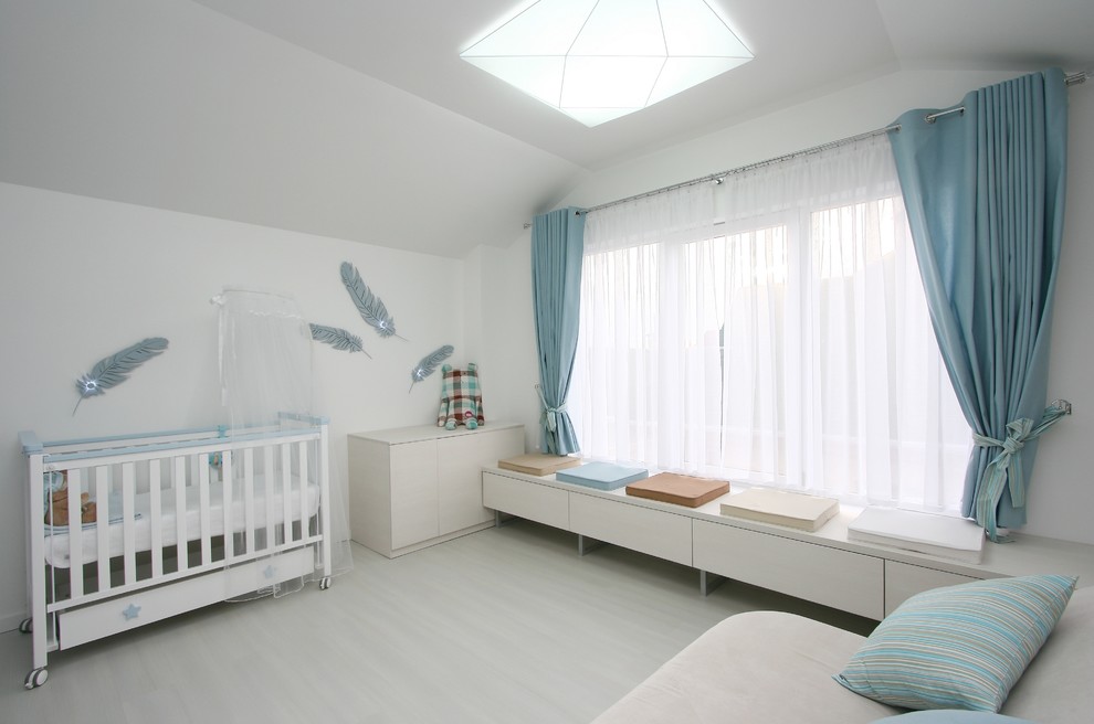Modelo de habitación de bebé neutra contemporánea grande con paredes blancas y suelo de madera pintada