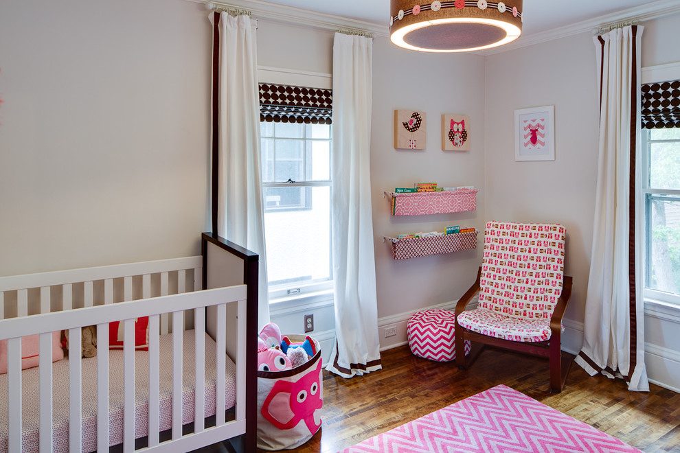 Foto de habitación de bebé niña actual con paredes beige y suelo de madera oscura