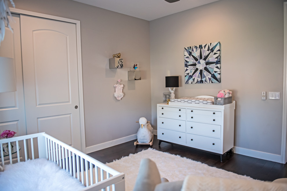 Foto di una piccola cameretta per neonata design con pareti multicolore e parquet scuro