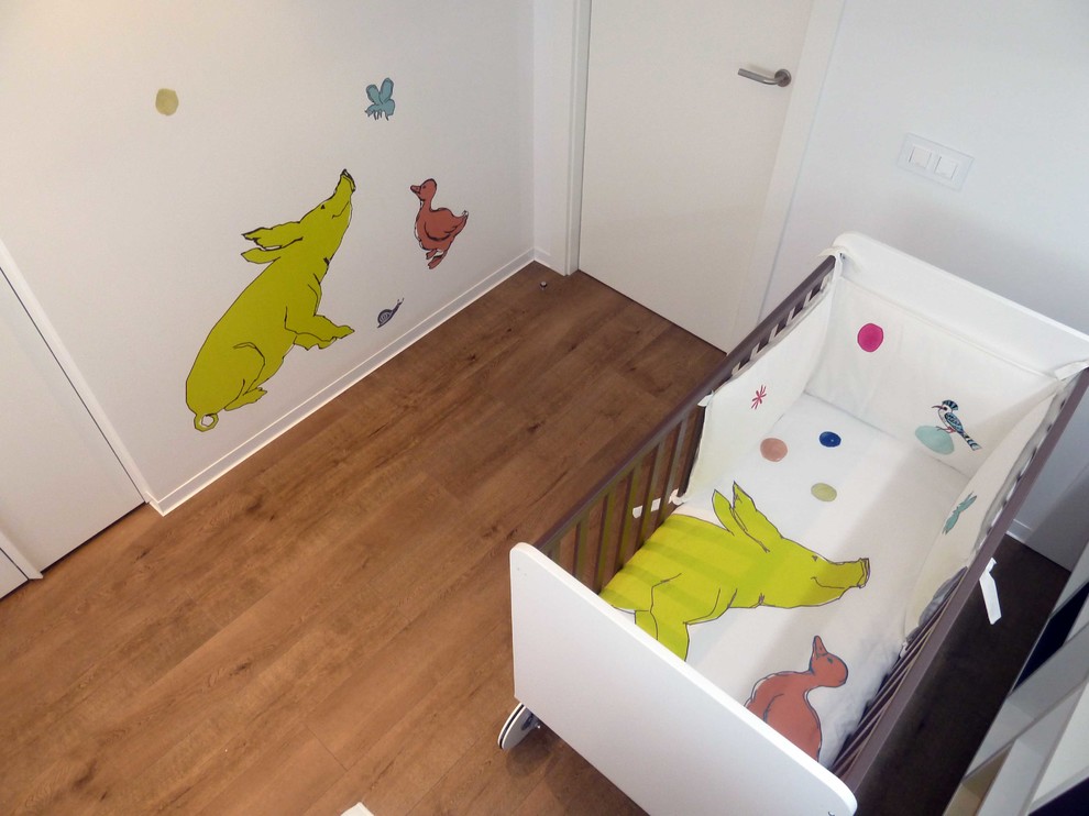 Immagine di una piccola cameretta per neonati neutra minimalista con pareti bianche e pavimento in legno massello medio