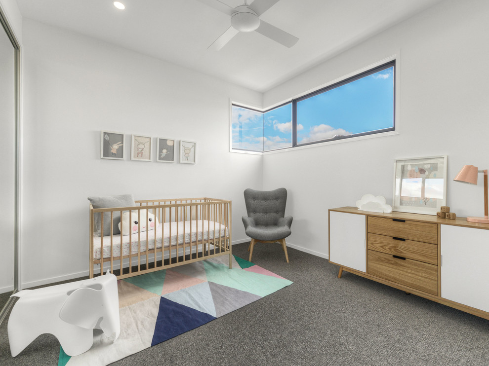Imagen de habitación de bebé neutra actual con paredes blancas y moqueta