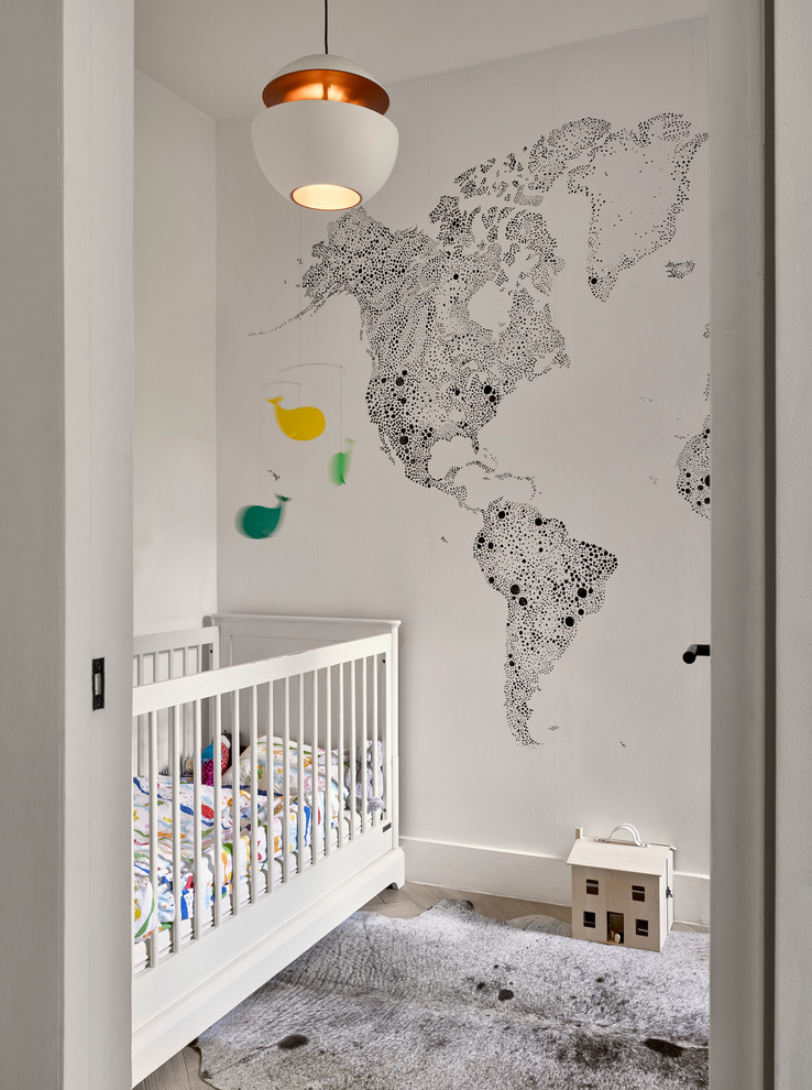 Contemporary gender neutral nursery in London with white walls, medium hardwood flooring, grey floors and a feature wall.