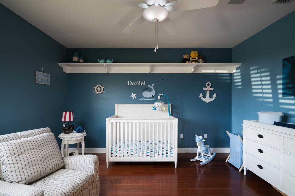 Cette image montre une chambre de bébé garçon traditionnelle de taille moyenne avec un mur bleu, parquet foncé et un sol orange.