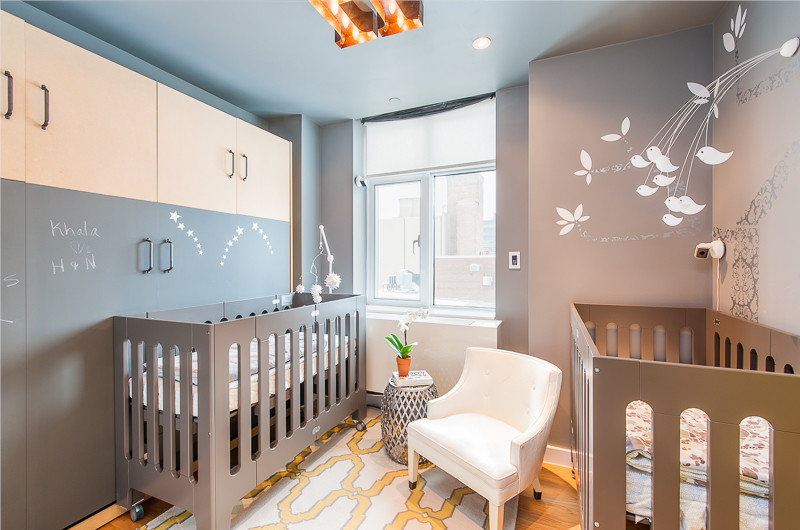 Cette image montre une petite chambre de bébé neutre bohème avec un mur gris et parquet clair.