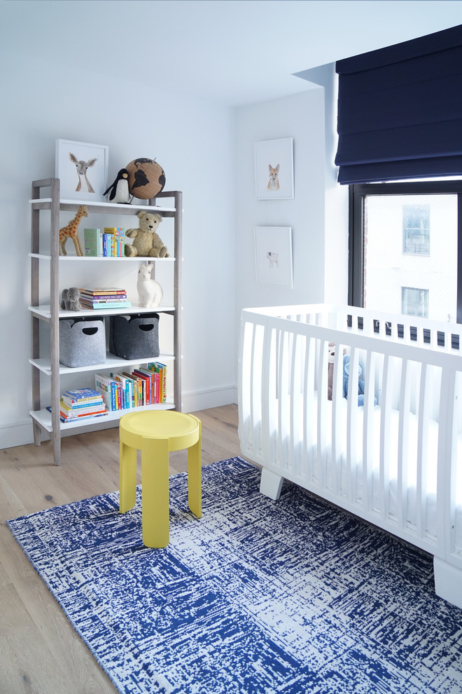 Inspiration for a mid-sized modern boy medium tone wood floor and brown floor nursery remodel in New York with white walls