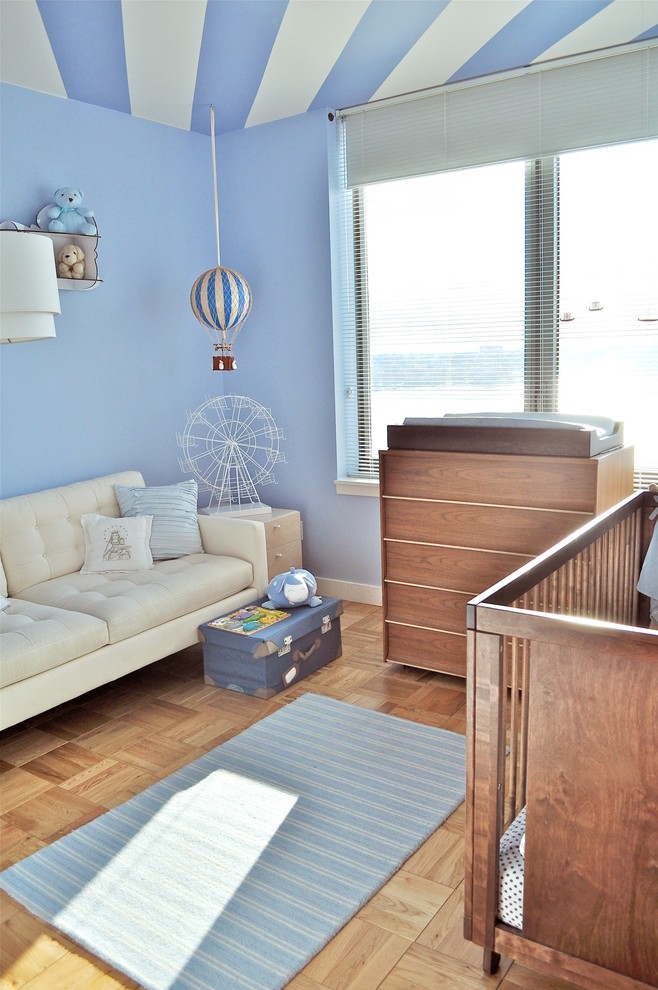 Modelo de habitación de bebé niño actual pequeña con paredes azules y suelo de madera clara