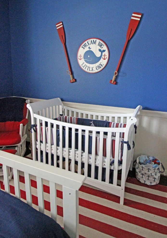 This is an example of a medium sized traditional nursery for boys in Dallas with blue walls and medium hardwood flooring.