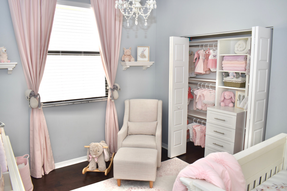 Ejemplo de habitación de bebé niña romántica pequeña con paredes grises, suelo de madera oscura, suelo marrón y papel pintado