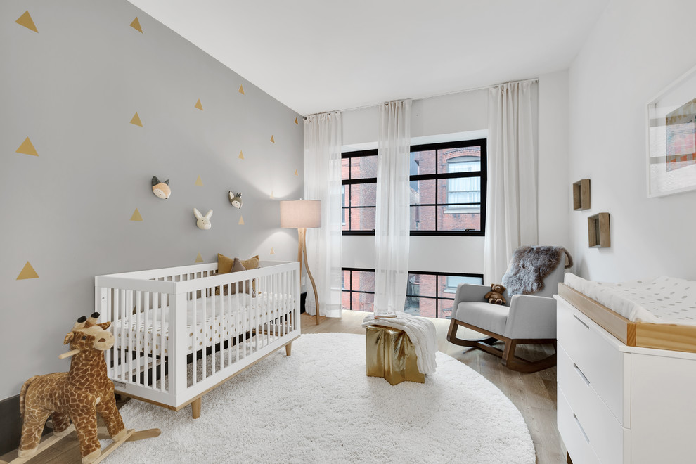 Contemporary nursery in New York with multi-coloured walls, light hardwood flooring and a feature wall.
